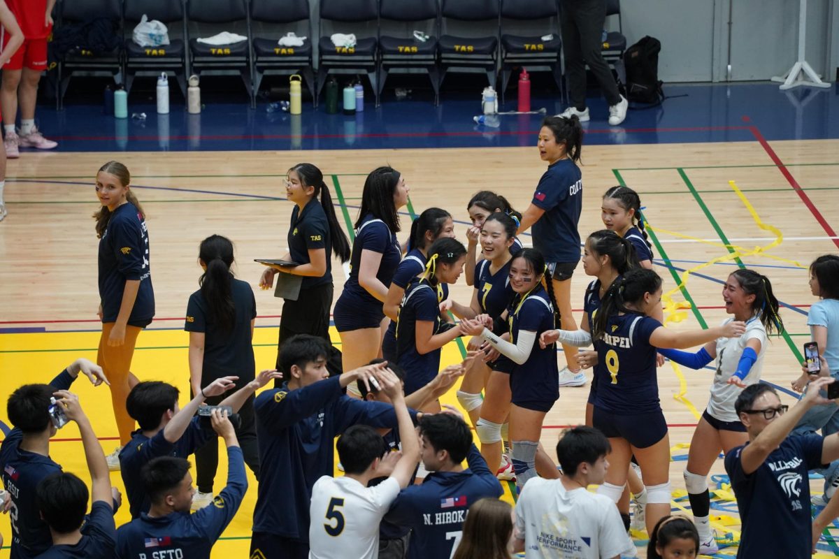 The TAS girl’s volleyball team celebrate with streamers and a human tunnel after winning the gold medal. [CHESTER DENNIS/THE BLUE & GOLD]